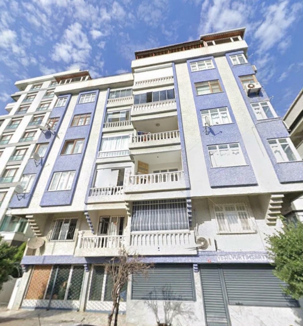 Mavi ve beyaz cepheli apartman binası.